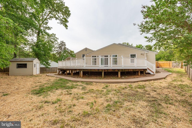 back of property with a wooden deck, a fenced backyard, a shed, a lawn, and an outbuilding