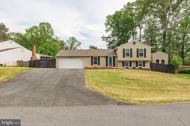 split level home with an attached garage, fence, a chimney, and aphalt driveway