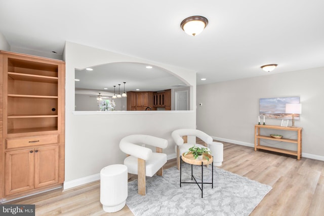 living area with baseboards, arched walkways, light wood-style flooring, and recessed lighting