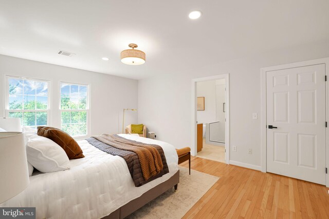 bedroom featuring light wood finished floors, recessed lighting, baseboards, and ensuite bath