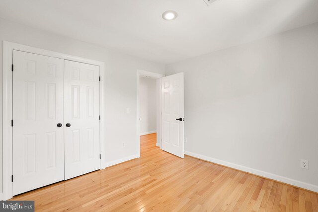 unfurnished bedroom with baseboards, wood finished floors, a closet, and recessed lighting