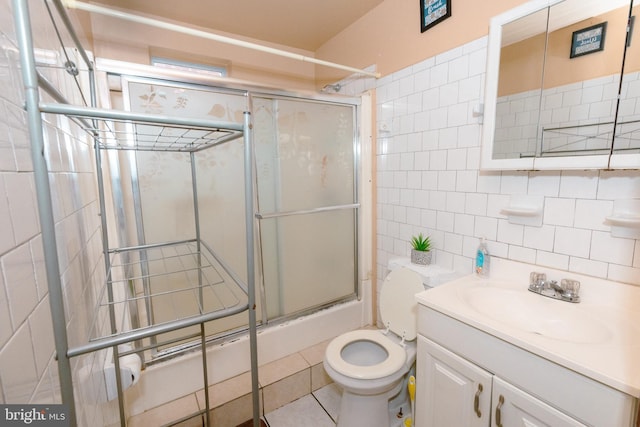 bathroom featuring tile walls, toilet, vanity, tasteful backsplash, and shower / bath combination with glass door