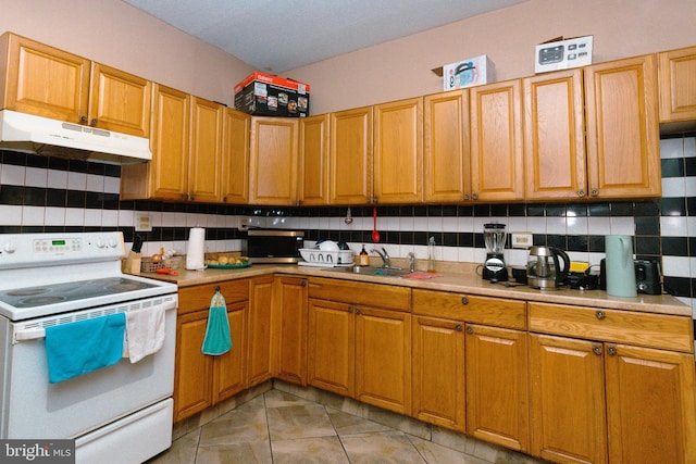 kitchen with white electric range oven, under cabinet range hood, a sink, backsplash, and light countertops