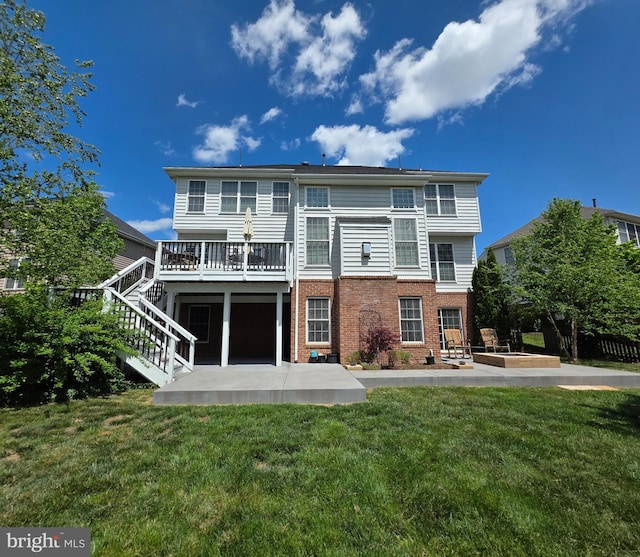 rear view of house with a deck, a patio, brick siding, a yard, and stairway