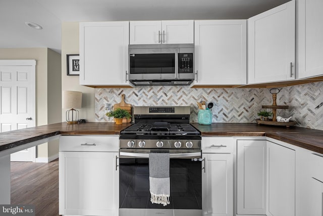 kitchen featuring decorative backsplash, wood finished floors, white cabinets, wood counters, and appliances with stainless steel finishes