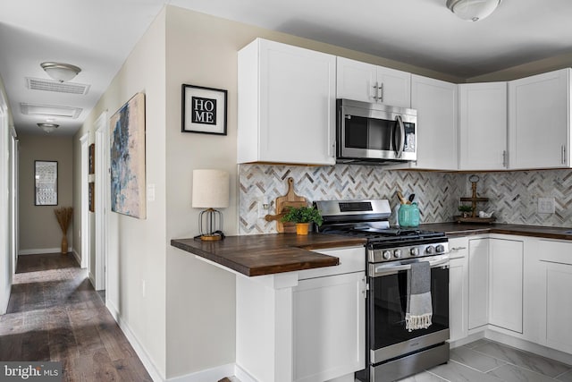 kitchen with white cabinets, stainless steel appliances, decorative backsplash, visible vents, and butcher block counters