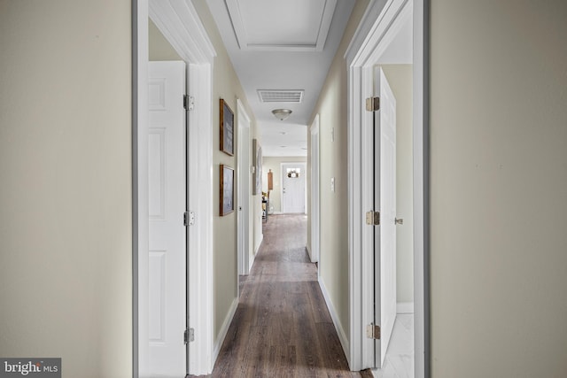corridor with baseboards, wood finished floors, and visible vents