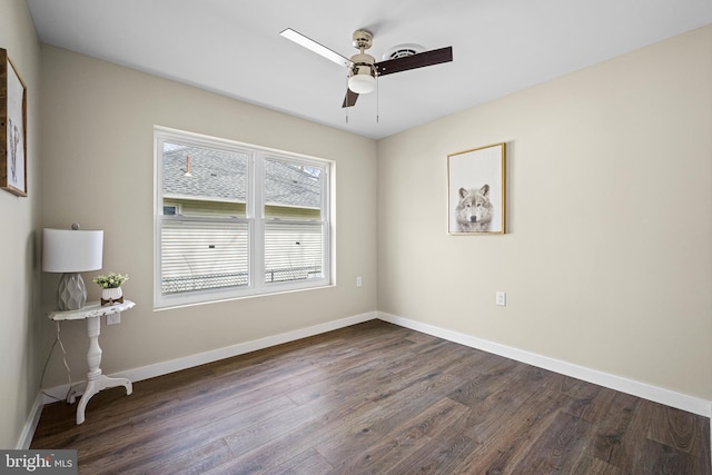 unfurnished room with dark wood-style flooring, a ceiling fan, and baseboards