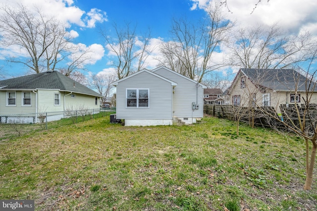 rear view of house featuring a lawn and a fenced backyard
