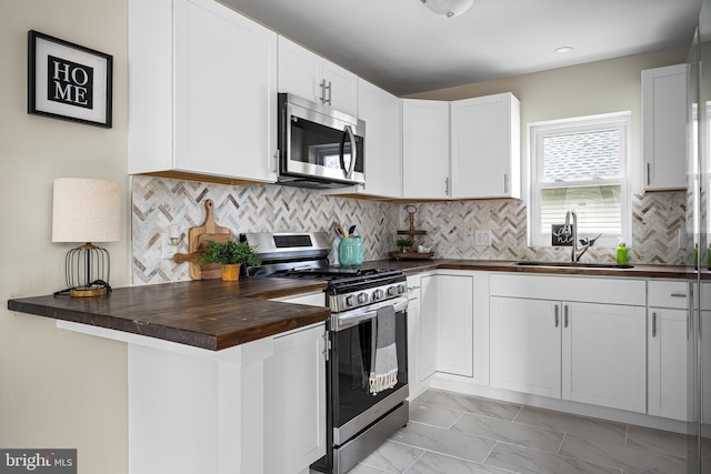 kitchen featuring a sink, butcher block counters, marble finish floor, stainless steel appliances, and white cabinetry