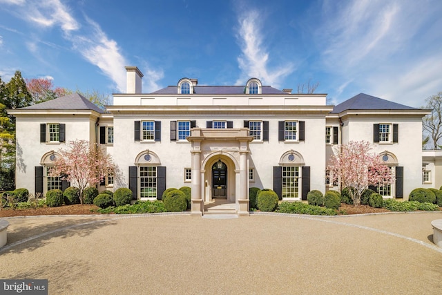 colonial house with a chimney and stucco siding
