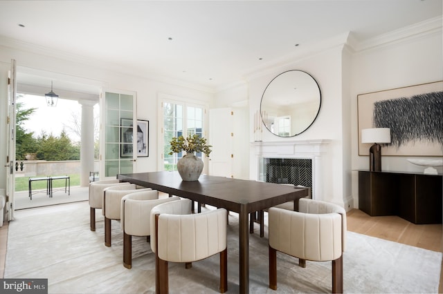 dining area with crown molding, a fireplace, and light wood-type flooring