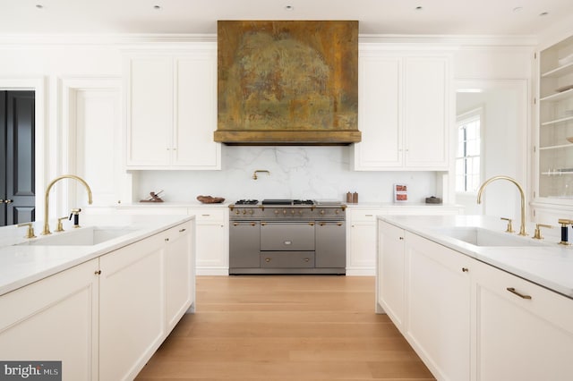kitchen featuring a sink, double oven range, light wood-style flooring, and white cabinetry