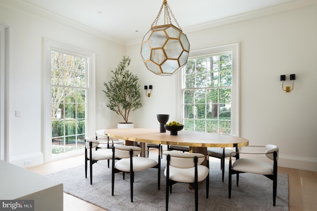 dining room featuring light wood-style floors, baseboards, plenty of natural light, and ornamental molding