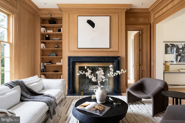 living area featuring plenty of natural light, ornamental molding, built in features, and a fireplace
