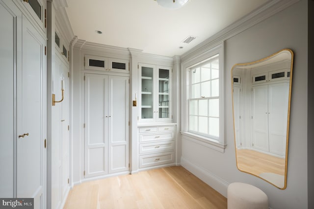 doorway featuring visible vents, ornamental molding, light wood finished floors, and baseboards