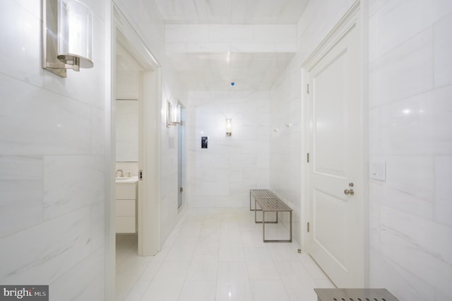 hallway with a sink and tile walls