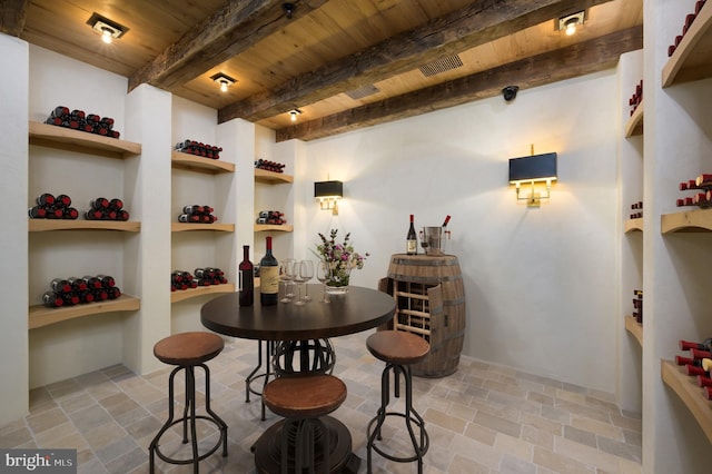 wine cellar featuring built in features, wood ceiling, beamed ceiling, and stone finish flooring