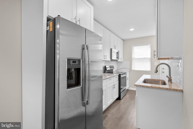 1414 N Bethel St, Baltimore, MD 21213 - kitchen featuring stainless steel appliances, a sink, backsplash, white cabinets, and wood finished floors