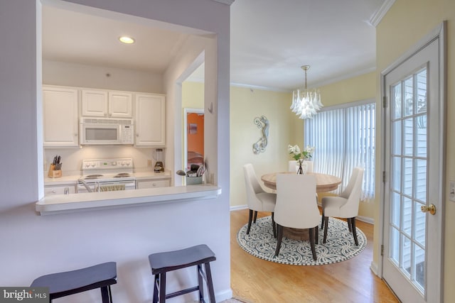 dining area featuring crown molding, light wood-style flooring, a chandelier, and a wealth of natural light