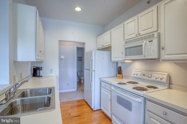 kitchen with light wood-type flooring, a sink, white cabinets, recessed lighting, and white appliances