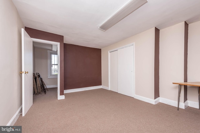 interior space with baseboards, light carpet, and a closet
