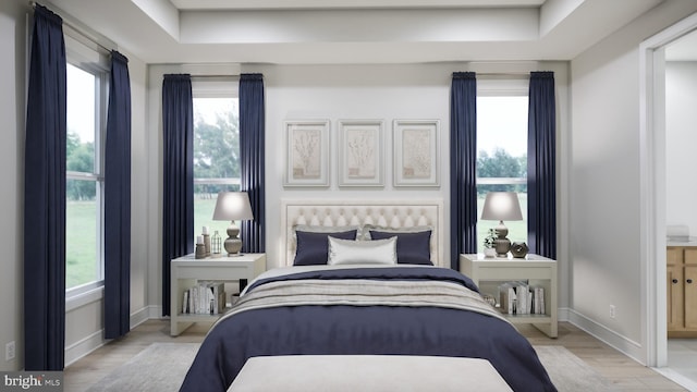 bedroom with baseboards, wood finished floors, and multiple windows