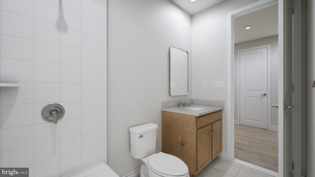 bathroom featuring vanity, a tile shower, tile patterned floors, and toilet