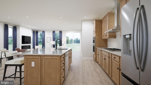 kitchen featuring a sink, light countertops, light brown cabinets, stainless steel appliances, and wall chimney exhaust hood