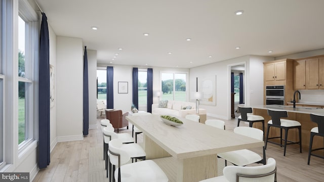 dining area with a water view, baseboards, recessed lighting, and light wood finished floors