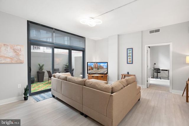 living room with visible vents, light wood finished floors, and baseboards