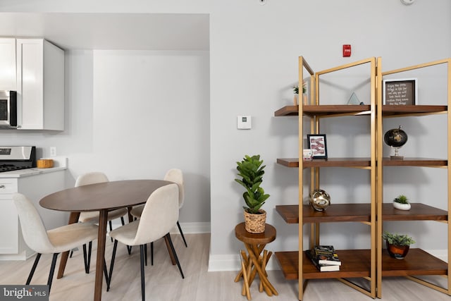 dining space with baseboards and light wood-style flooring