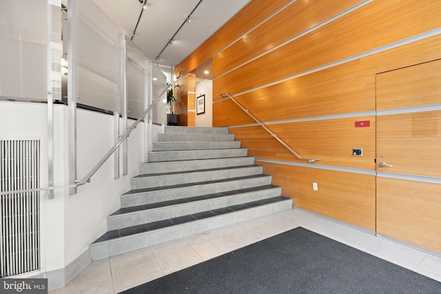 stairs featuring track lighting and tile patterned floors