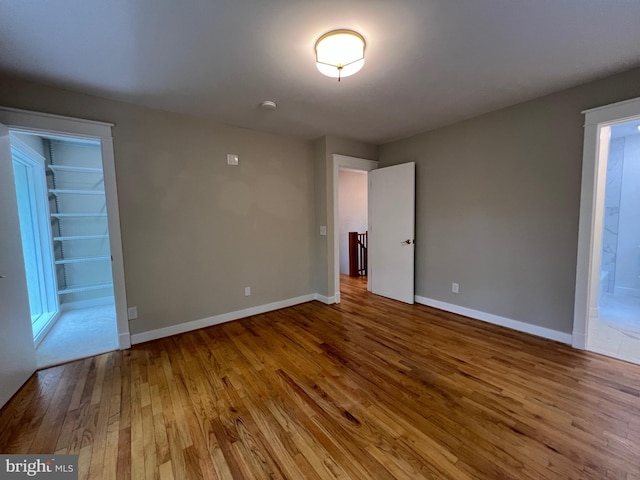 8122 Stacey Rd, Alexandria, VA 22308 - unfurnished bedroom featuring baseboards, a walk in closet, and wood finished floors