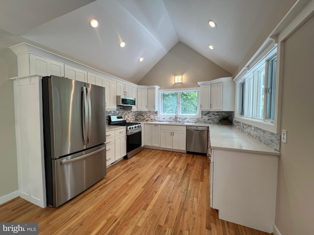 8122 Stacey Rd, Alexandria, VA 22308 - kitchen featuring stainless steel appliances, vaulted ceiling, light wood-style flooring, white cabinetry, and light countertops