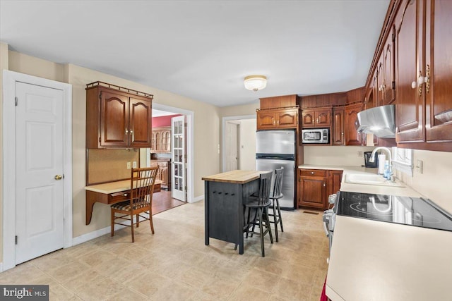 3161 Grande Oak Pl, Lancaster, PA 17601 - kitchen featuring brown cabinets, a sink, baseboards, under cabinet range hood, and appliances with stainless steel finishes