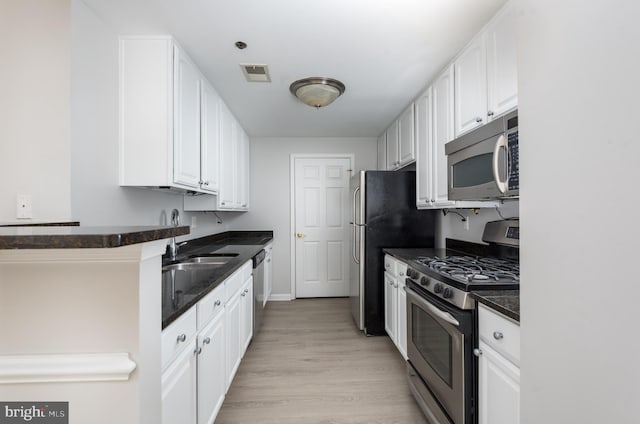 kitchen featuring visible vents, appliances with stainless steel finishes, baseboards, white cabinets, and light wood-style floors