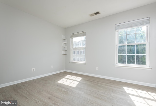 empty room with baseboards, visible vents, and light wood-style flooring