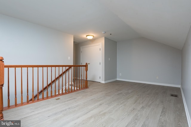 additional living space with visible vents, baseboards, lofted ceiling, and wood finished floors