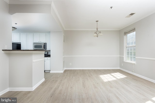 unfurnished living room featuring baseboards, ornamental molding, light wood finished floors, and a chandelier
