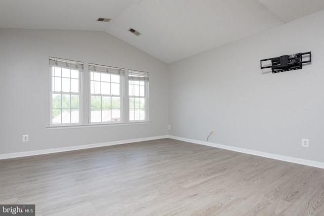 empty room featuring visible vents, baseboards, wood finished floors, and vaulted ceiling