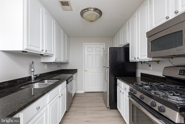 kitchen featuring visible vents, a sink, light wood-style floors, stainless steel appliances, and white cabinetry