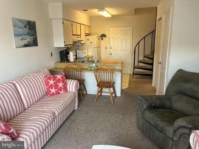 carpeted living room featuring a sink and stairway