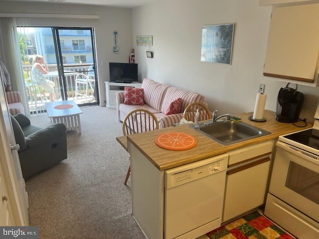 kitchen with a peninsula, white appliances, light countertops, a sink, and carpet