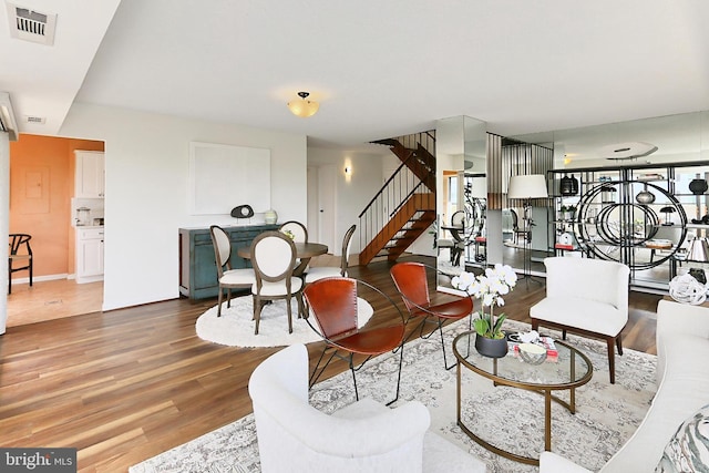living area featuring stairs, baseboards, visible vents, and wood finished floors