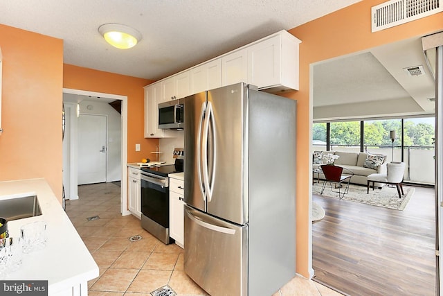 kitchen with light countertops, stainless steel appliances, visible vents, and white cabinetry