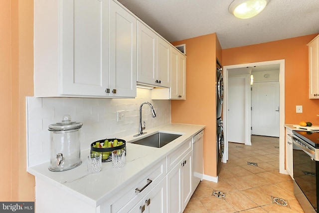 kitchen with stacked washer and dryer, a sink, backsplash, stainless steel electric stove, and dishwashing machine