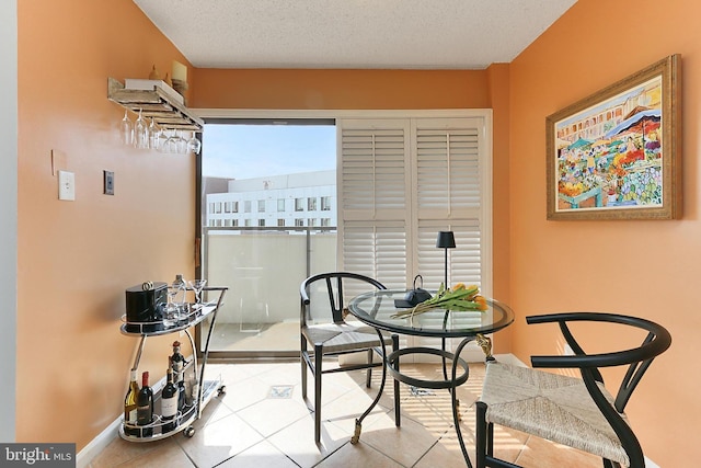 dining area with tile patterned flooring, a textured ceiling, and baseboards