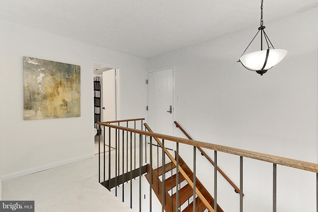 corridor with baseboards, carpet flooring, and an upstairs landing