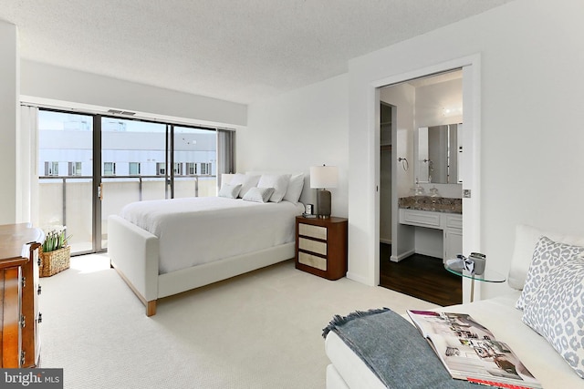 bedroom with carpet flooring, a textured ceiling, ensuite bath, and access to exterior